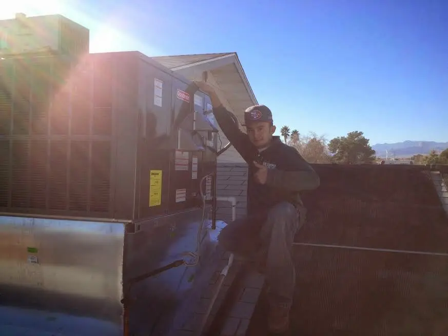 HVAC technician performing Air Duct Cleaning on a rooftop unit in Carrollton